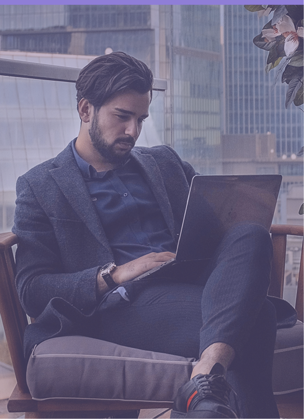 Homem sentado em poltrona trabalhando em um notebook