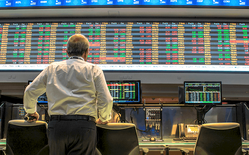 homem em pé acompanhando as ações da bolsa de valores brasileira