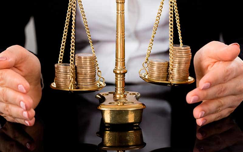 balança com moedas douradas sendo equilibradas por uma mulher
