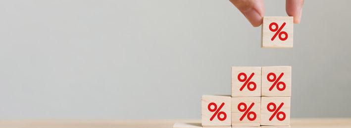 Interest rate financial and mortgage rates concept. Hand putting wood cube block increasing on top with icon percentage symbol upward direction