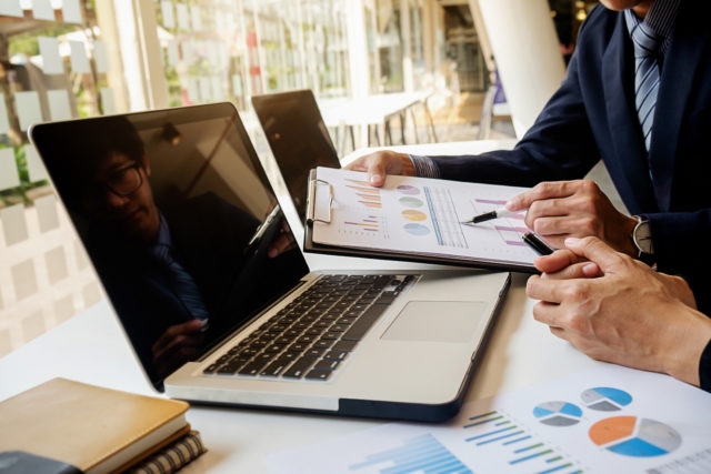 Business concept. Business people discussing the charts and graphs showing the results of their successful teamwork. Selective focus.